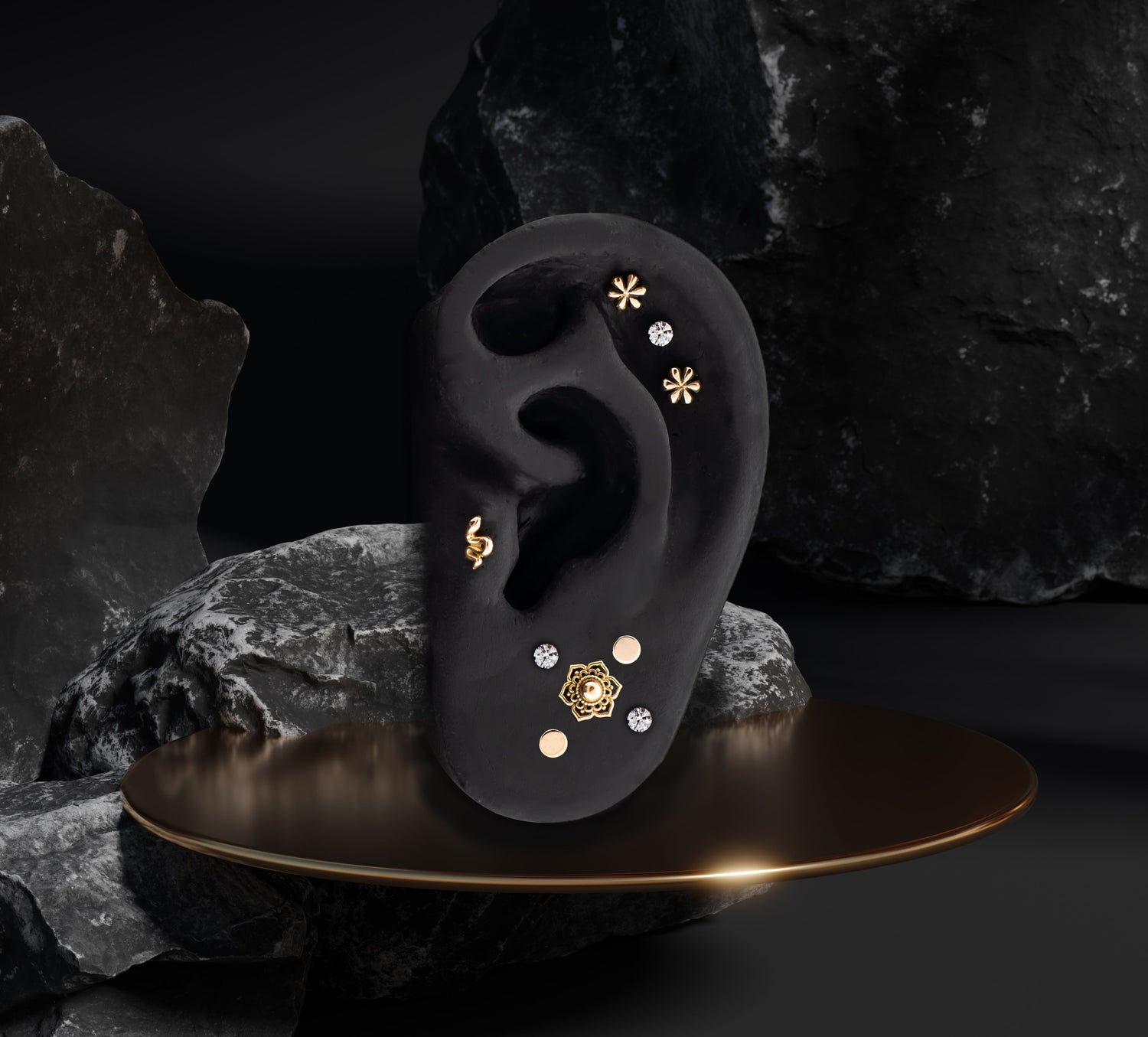 Silicone ear with 18Kt gold jewelry displayed on a gold pedestal with black rocks in the background